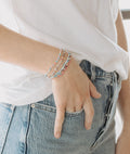Person wearing colorful beaded bracelets on a plain background